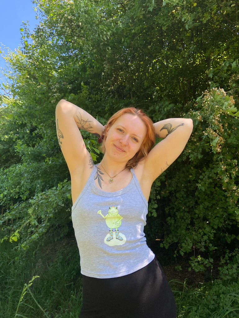 Het vrouwelijke model draagt een grijze tanktop met een kikkerprint. 