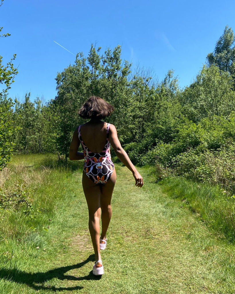 achterkant.  Model draagt zwart badpak met konijntjes print in roze en oranje.