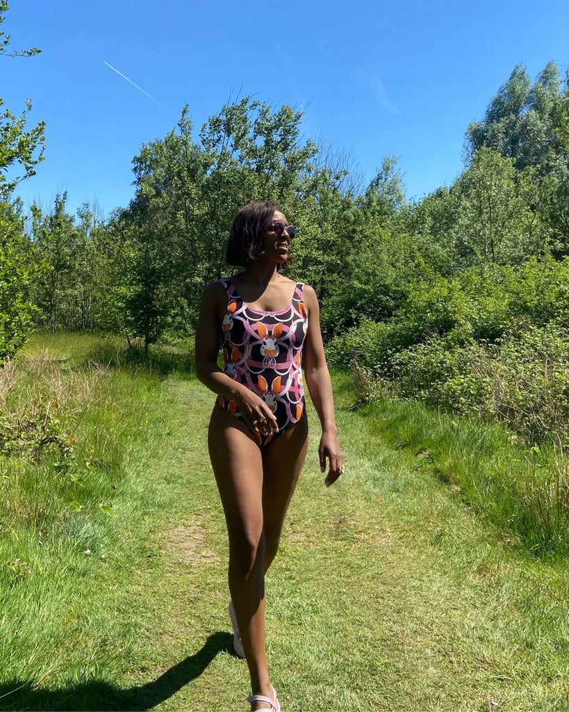 Vooraanzicht. Model draagt zwart badpak met konijntjes print in roze en oranje.