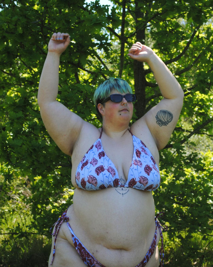 Zij aanzicht van de koordbikini. Model draagt de blauwe bikini top en rode bikini broekje in matching bloemenprint. 