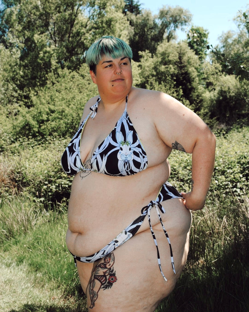 Vooraanzicht. Het model  draagt de zwarte koordbikini met een konijntjes print in blauw. 
